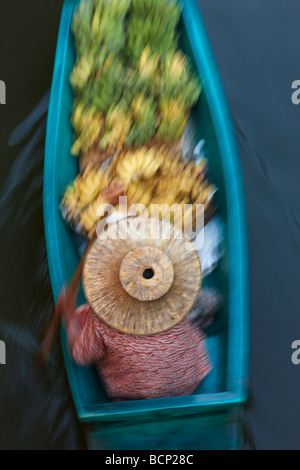 eine Frau paddeln ein Schiff, beladen mit Bananen auf dem schwimmenden Markt in Damnoen Saduak, Bangkok, Thailand Stockfoto