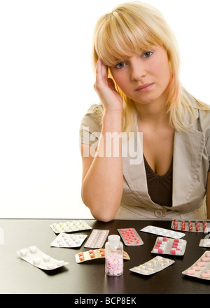 Junge Frau Mit Kopfschmerzen Sitzt ein Einem Tisch Mit Vielen Arzneimitteln Stockfoto