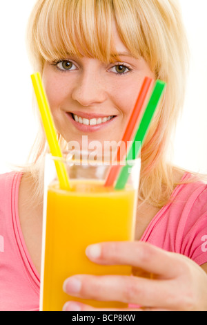 Junge blonde Frau Hält Ein Glas Orangensaft Mit Drei Bunton Strohhalmen in Die Kamera Stockfoto