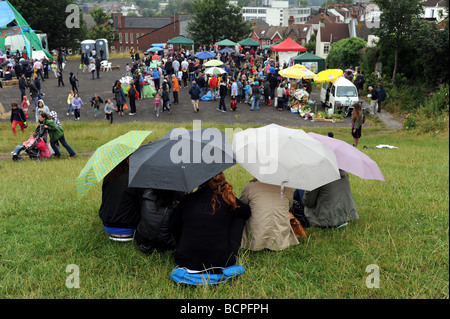 Kauern unter Sonnenschirmen, trocken halten, bei der Patchfest Community-Event in Brighton Stockfoto