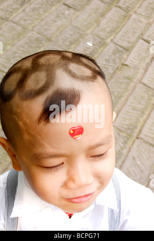 Chinesische junge mit Olympia-Logo Haare schneiden, Peking, China Stockfoto