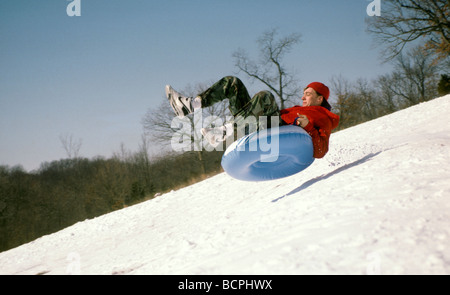 Teenager nimmt Luft: Rodeln oder Schläuche für Winterspaß steil bergab nach Schneefall. Midwest USA Stockfoto