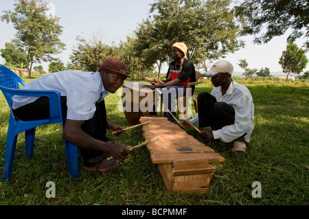 Drei Männer spielen traditionelle Instrumente in einer Zivilgesellschaft Zeremonie im ländlichen Uganda Stockfoto