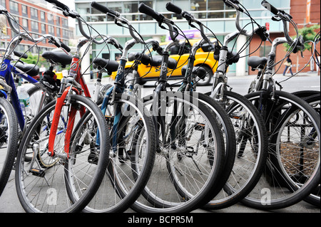 Fahrräder auf einem städtischen Bürgersteig geparkt Stockfoto