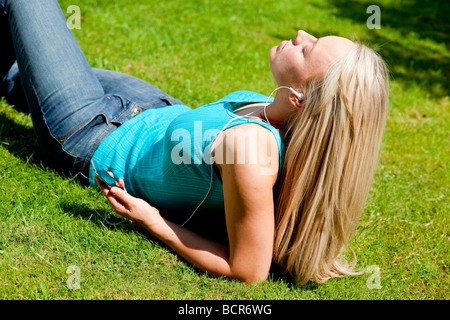 Mädchen liegend auf dem Rasen, anhören von MP3-player Stockfoto