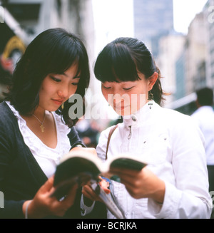 Junge asiatische Frauen Touristen betrachten eine NYC Reiseführer und eine Karte auf der 5th Avenue in New York City, NY USA Stockfoto