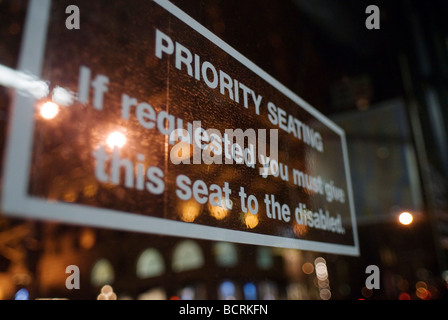 Eine Priorität Sitzgelegenheiten Zeichen Sitzplatzreservierung für Menschen mit Behinderungen ist in einem New Yorker Bus gesehen. Stockfoto