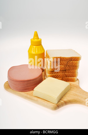 Zutaten für eine Bologna und Käse Sandwich mit Stapel von Wurstwaren, Käse, Brot und Senf auf Holz board Stockfoto