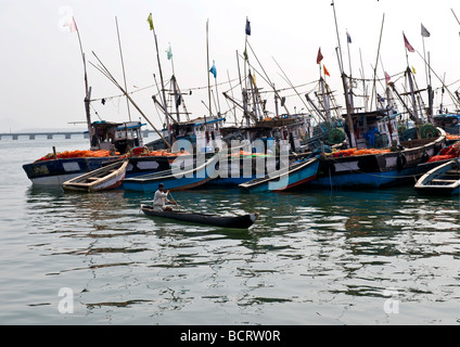 Mann in einem Kanu patrouillieren gewartet indische Angelboote/Fischerboote verankert und gebunden in der Schlange am Kai bereit, zum Angeln in der Nacht fahren. Stockfoto