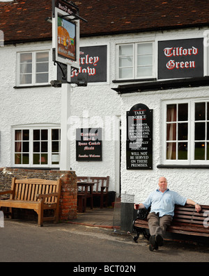 Ein Mann einen Drink außerhalb der Gerste Mähen Gastwirtschaft, Tilford, Farnham, Surrey, England, UK. Stockfoto