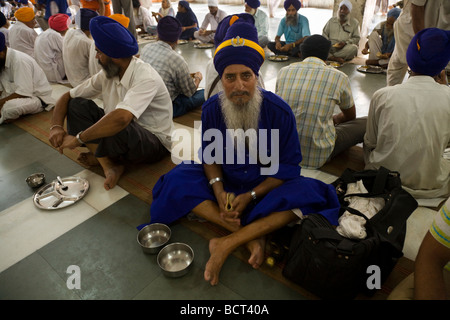 Sikh Mann wartet eine kostenlose Mahlzeit in der Gemeinschaftsküche in den goldenen Tempel (Sri Harmandir Sahib) Essen Amritsar. Indien. Stockfoto