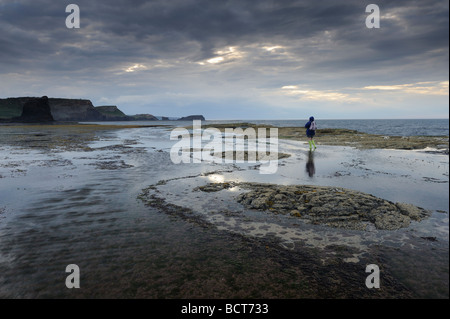 Eine einsame Figur mit Blick auf schwarze Nab in der Nähe von Whitby an der Ostküste von Yorkshire, England, UK Stockfoto