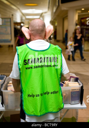Ein Freiwilliger der Wohltätigkeitsorganisation The Samaritans, der Spenden gesammelt hat, während er große falsche Plastikohren trägt. Stockfoto