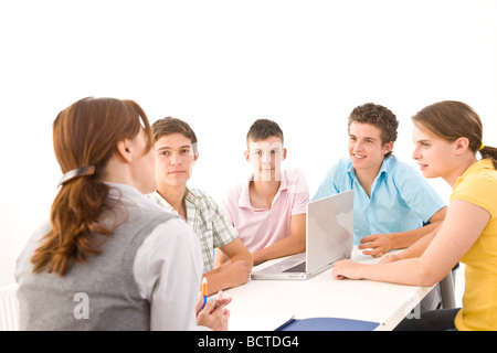 Gruppe von Jugendlichen, die mit ihrem Trainer an einem Tisch sitzen Stockfoto