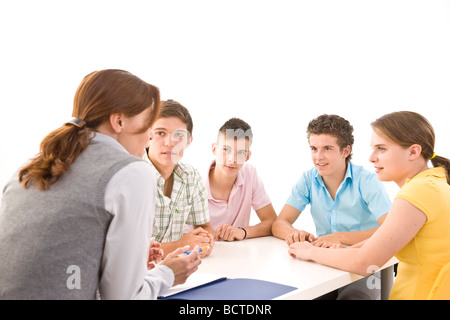 Gruppe von Jugendlichen, die mit ihrem Trainer an einem Tisch sitzen Stockfoto