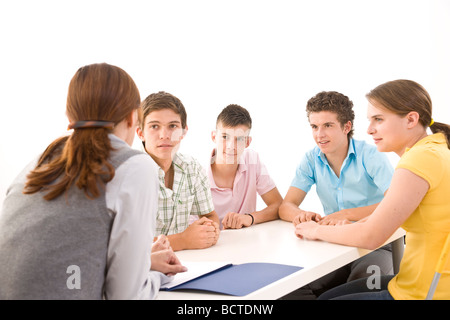 Gruppe von Jugendlichen, die mit ihrem Trainer an einem Tisch sitzen Stockfoto