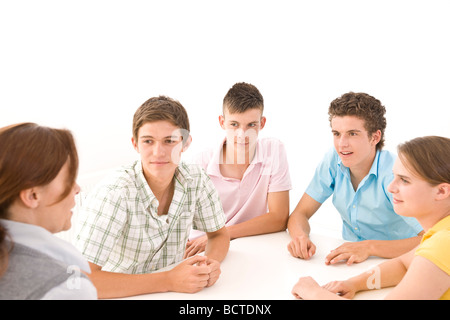 Gruppe von Jugendlichen, die mit ihrem Trainer an einem Tisch sitzen Stockfoto