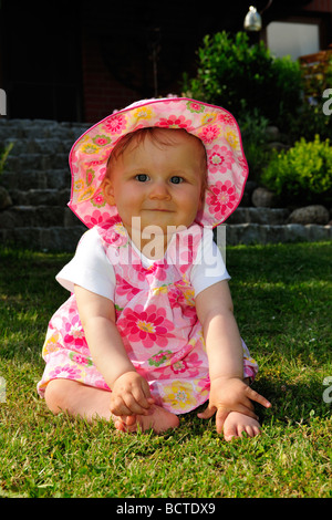 Kleinkind auf dem Rasen im Garten sitzen und spielen Stockfoto