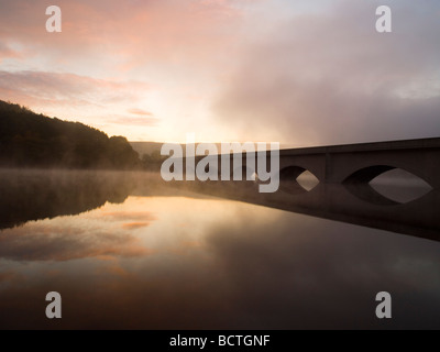 Nebel auf dem Wasser und der A57-Brücke bei Sonnenaufgang am Ladybower Vorratsbehälter spiegelt sich im Wasser, Derbyshire England UK Stockfoto