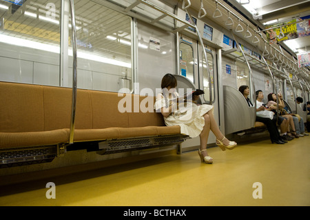 Ein Pendler mit einem Mobiltelefon in einer u-Bahn u-Bahn in Tokio Stockfoto