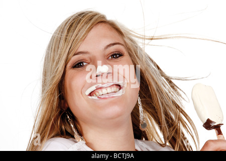 Junge Frau Essen ein Eis am Stiel, Gesicht bedeckt mit Eis Stockfoto