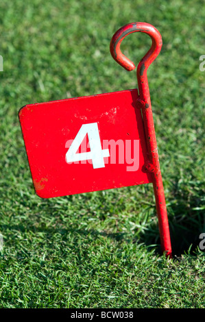 Rote Nummer 4 Metall Minigolf Pflock im Loch auf einer Grünfläche Stockfoto