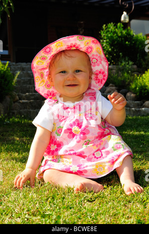 Kleinkind auf dem Rasen im Garten sitzen und spielen Stockfoto