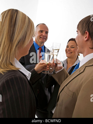 Team, zwei Männer und zwei Frauen, klirrende Gläser Sekt trinken zu ihrem Erfolg Stockfoto