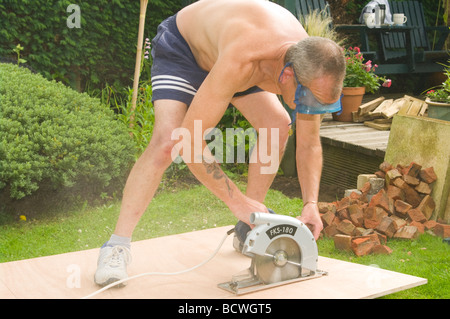 Handwerker, die ein Blatt aus Holz mit einer Kreissäge schneiden Stockfoto