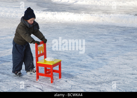 kleines Kind üben mit Stuhl auf Natureis Stockfoto