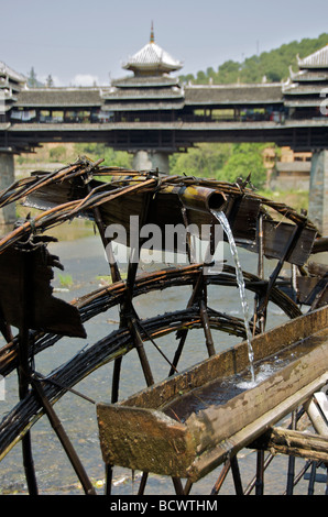 Alten Wasserrad noch für die Bewässerung genutzt mit Chenyang Wind und Regen Brücke im Hintergrund Sanjiang Guangxi China Stockfoto