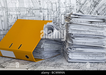Gelbe Dateiordner und Haufen von Konstruktionszeichnungen liegen auf dem Tisch. Unternehmen Still-Leben. Stockfoto