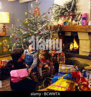 HERR 4 KINDER ÖFFNEN WEIHNACHTSGESCHENKE UNTER DEM WEIHNACHTSBAUM Stockfoto