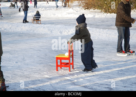 kleines Kind üben mit Stuhl auf Natureis Stockfoto