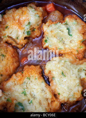 Hautnah auf traditionelle britische Talg Knödel mit Petersilie oben auf ein Rindergulasch in einer Stahl-Pfanne Kochen Stockfoto