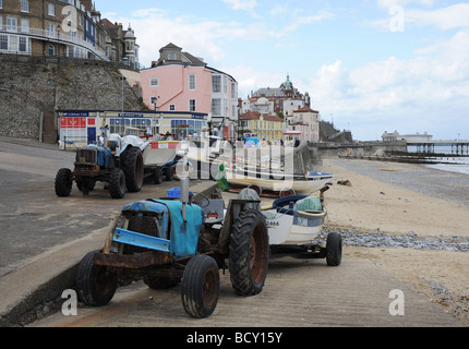 Ramponierte alte Traktoren ziehen die Fischerboote am Strand im Badeort von Cromer an der Küste von North Norfolk UK Stockfoto