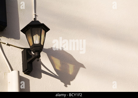 Ein traditionelles Wand Außenleuchte mit lang anhaltenden, niedrige Energie Birne, wirft einen Schatten an der Wand. VEREINIGTES KÖNIGREICH. Stockfoto