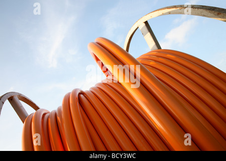 Orangefarbene Kabel für Breitbandverbindungen auf einem Stahlseil Trommel vor blauem Himmel. Stockfoto