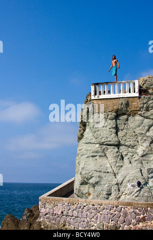 Junger Mann taucht aus Betonplattform in Wasser als Touristen Uhr entlang des Malecon, Mazatlan, Mexiko Stockfoto