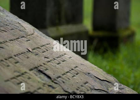 gebrochene hebräische Inschrift auf geneigten Grabstein auf verlassenen jüdischen Friedhof, Essen-Kettwig, Deutschland Stockfoto