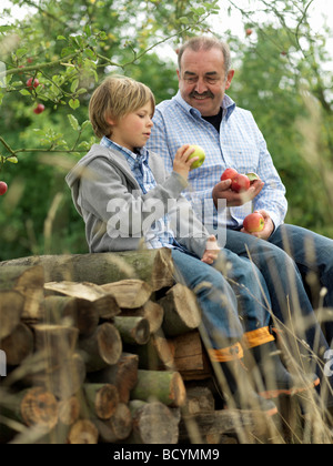 Mann und der junge mit Äpfeln, sitzen auf Protokolle Stockfoto