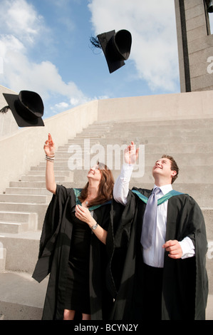 Zwei 2 Aberystwyth University Studenten Abschlusstag werfen ihre Mützen in die Luft in der Feier Wales UK Stockfoto