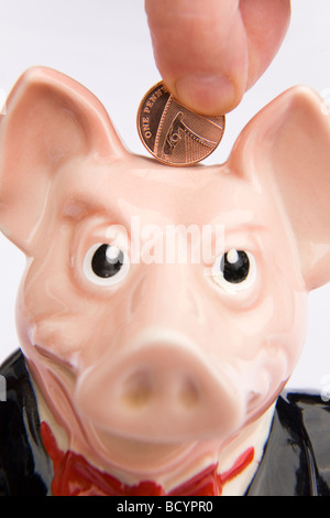 Ein Mann legt einen Cent in ein Sparschwein. Dies gehört zu einer Reihe von fünf Sparschweine in den 1980er Jahren von der NatWest Bank produziert. Stockfoto