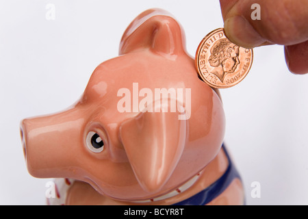 Ein Mann legt einen Cent in ein Sparschwein. Dies ist Maxwell, eines aus einer Reihe von fünf Sparschweine in den 1980er Jahren von der NatWest Bank produziert. Stockfoto