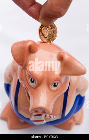 Ein Mann legt einen Cent in ein Sparschwein. Dies ist Maxwell, eines aus einer Reihe von fünf Sparschweine in den 1980er Jahren von der NatWest Bank produziert. Stockfoto