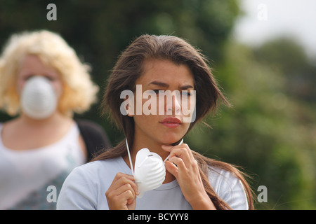 zwei junge Frauen in Straße tragen Filter Masken ein Niesen Stockfoto