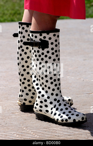 Frau im roten Kleid schwarz-weiß gefleckte Gummistiefel tragen Stockfoto