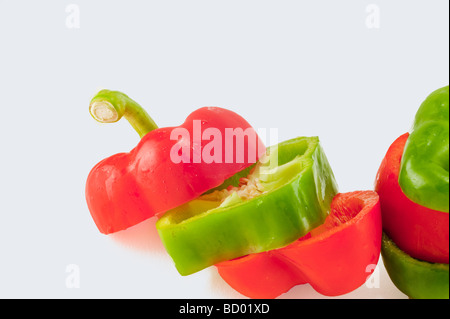 rote und grüne Paprika in Scheiben geschnitten und gestapelt in wechselnden Farben isoliert auf weiss Stockfoto