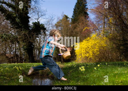 Junge springt über den Creek mit Korb Stockfoto