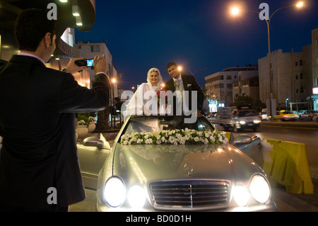 Eine jordanische Braut und Bräutigam posiert in einem silbernen Mercedes-Benz mit einem üppigen Arrangement aus weißen und rosa Blumen in Amman Jordan Stockfoto